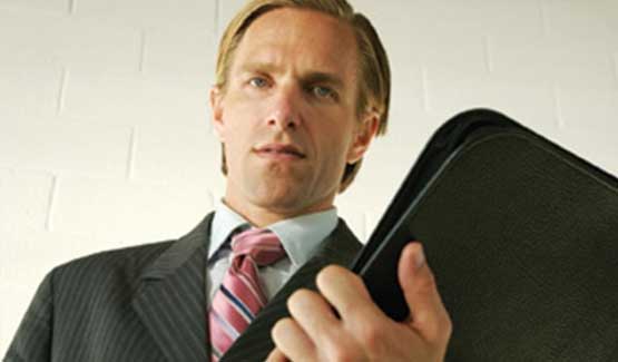 Male in suit with folder in his hand looking down, insinuating that he is referencing a tenant.