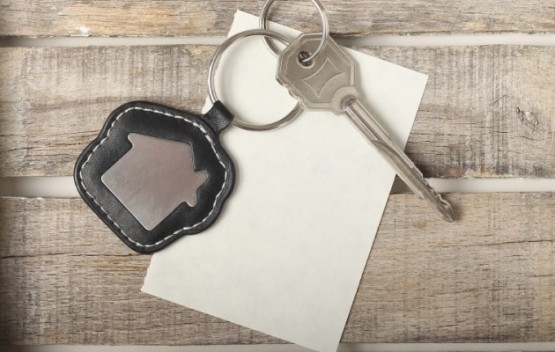 Key with fob on top of piece of paper on a wooden table.