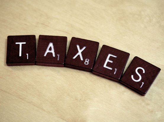 Non-Resident Landlord – Tax reminder for overseas landlords Small wooden squares in a row on a wooden surface spelling out the word taxes.
