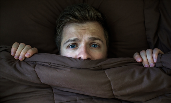 Man hiding under the covers having heard property news