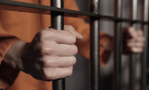 Landlord in prison with hands on bars